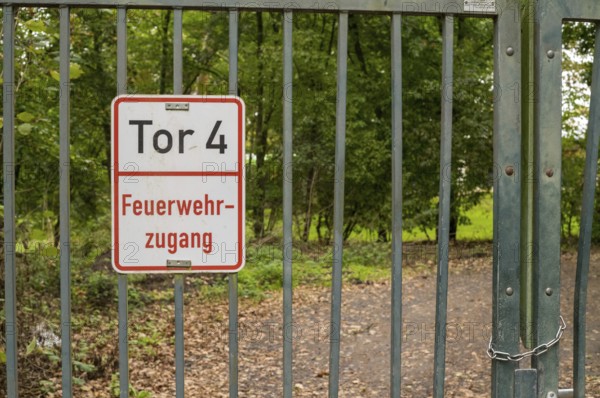 Borken, NRW, Germany, Metal gate displaying a feuerwehrzufahrt sign, providing entry to a forest path