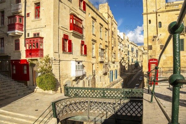 Street with incredible historic houses with colorful wooden balconies in La Valletta, capital city of Malta, bridge of Victoria Gate