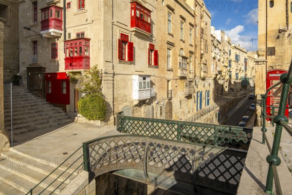Street with incredible historic houses with colorful wooden balconies in La Valletta, capital city of Malta, bridge of Victoria Gate