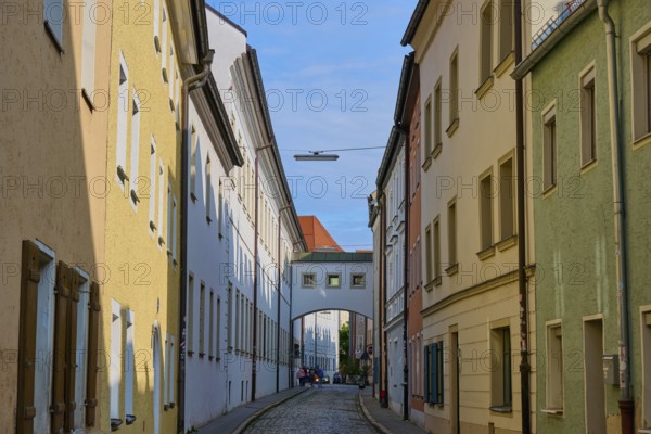 Narrow cobblestone alleyway between colourful historic buildings under a clear sky, Waffnergasse, Regensburg, Bavaria, Germany