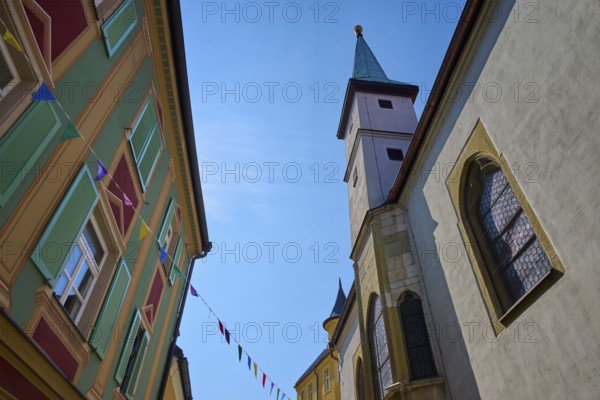 Building with coloured flags, church tower and historical architecture under the sky, Regensburg, Bavaria, Germany