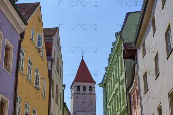 Colourful buildings and church tower along a busy street under a clear sky, Regensburg, Bavaria, Germany