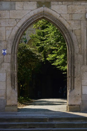 Historic stone gate with a view of a shady garden area behind it, Regensburg, Bavaria, Germany