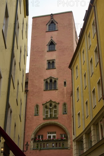 High tower with ornate windows between tall, narrow buildings, Regensburg, Bavaria, Germany