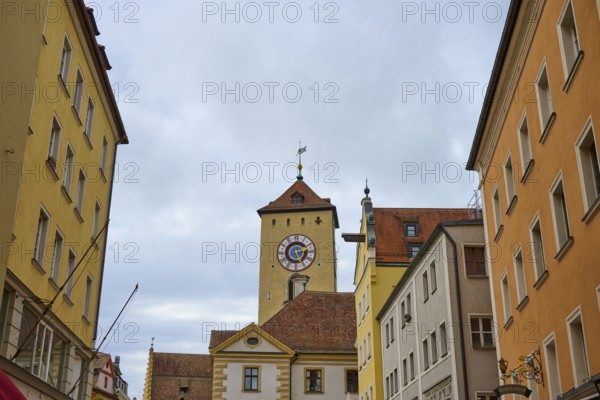 Street scene with a striking tower between historic buildings on a cloudy day, Regensburg, Bavaria, Germany