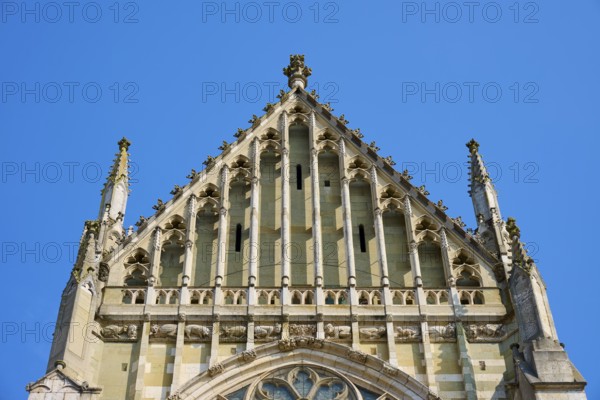 Decorated Gothic façade with window and roof spire under a clear sky, St Peter's Cathedral, Regensburg, Bavaria, Germany