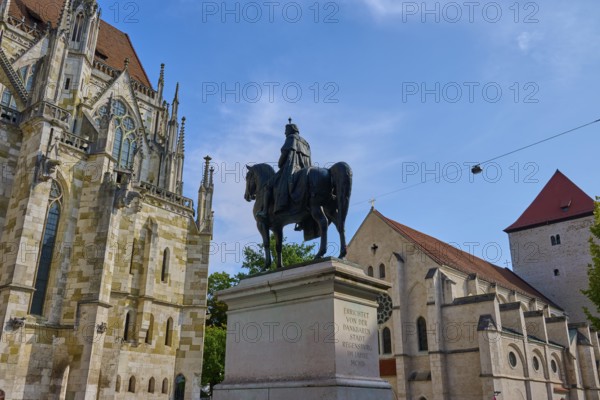 Equestrian statue in front of a historic church under a blue sky, St Peter's Cathedral, Regensburg, Bavaria, Germany