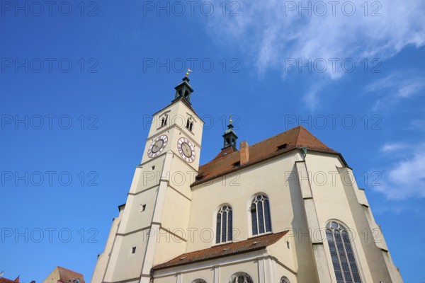 View of a church with a prominent steeple and clock against a clear blue sky, Neupfarrkirche, Regensburg, Bavaria, Germany