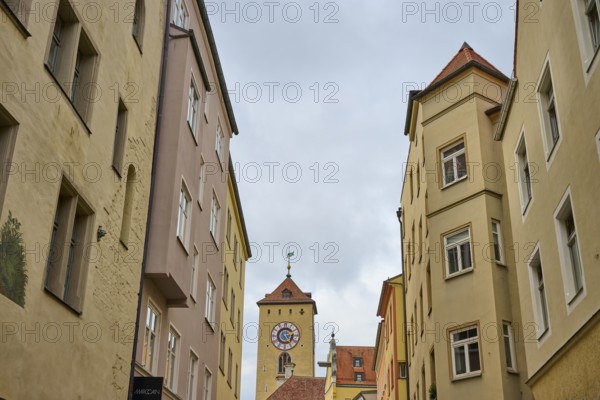 View of a tower through narrow alleys of historic buildings under a grey sky, Regensburg, Bavaria, Germany