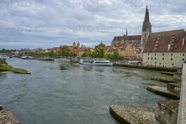 Panorama of a city with cathedral on the riverbank in a cloudy sky, Stone Bridge, Danube, Regensburg, Bavaria, Germany