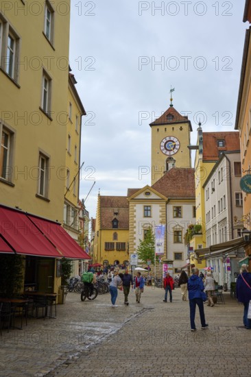 Lively pedestrian zone with a view of the tower, surrounded by historic buildings, Regensburg, Bavaria, Germany