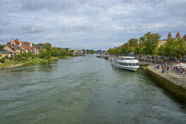 River landscape with boats and houses along the shore under a cloudy sky, Danube, Regensburg, Bavaria, Germany