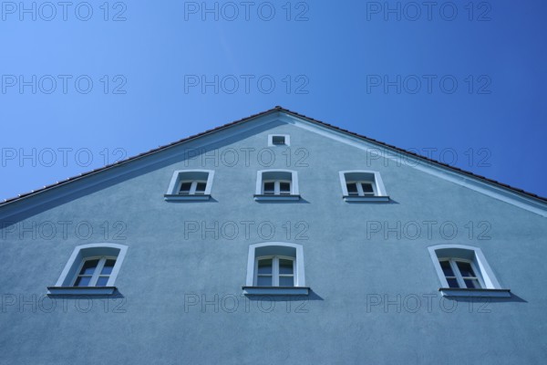 Blue house with several windows and sloping roof in front of a bright blue sky, Regensburg, Bavaria, Germany