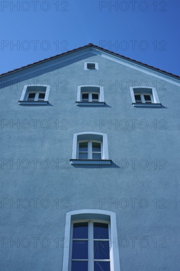Facade of a blue house with symmetrical windows under a blue sky, Regensburg, Bavaria, Germany