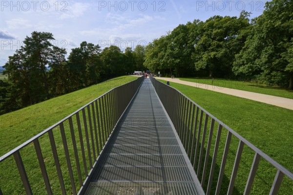 A metal bridge leads symmetrically towards a green wooded area, Walhalla, Donaustauf, Regensburg, Bavaria, Germany