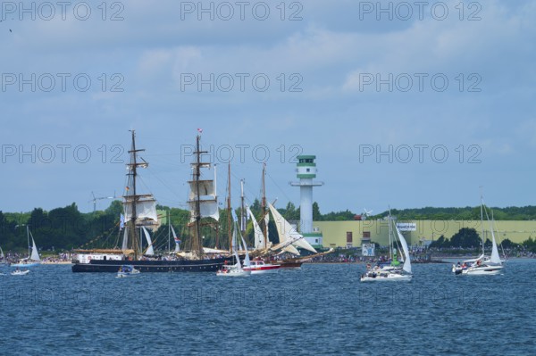 Large traditional sailing ship surrounded by sailing boats on the sea near Friedrichsort lighthouse, Windjammer Parade Kiel 2025, Plön district, Kiel Fjord, Schleswig-Holstein, Germany