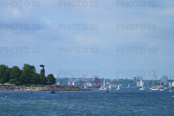 Boats and yacht on the sea near a tree-covered shore with people, Windjammer Parade Kiel 2025, Heikendorf, Plön district, Kiel Fjord, Schleswig-Holstein, Germany