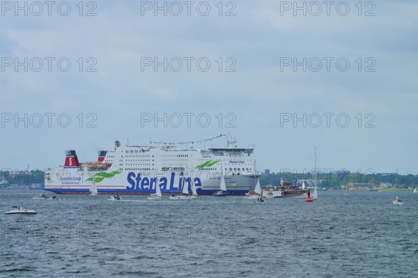 Large Stena Line ferry on the sea, surrounded by smaller sailing boats under a cloudy sky, Windjammer Parade Kiel 2025, Heikendorf, Kreis Plön, Kieler Förde, Schleswig-Holstein, Germany