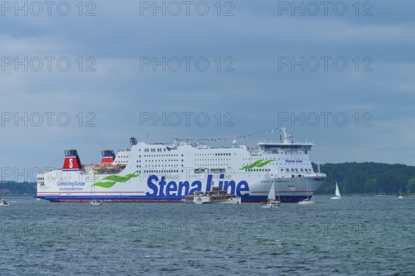 Stena Line ferry surrounded by sailing boats on the sea under a cloudy sky, Windjammer Parade Kiel 2025, Heikendorf, Kreis Plön, Kieler Förde, Schleswig-Holstein, Germany