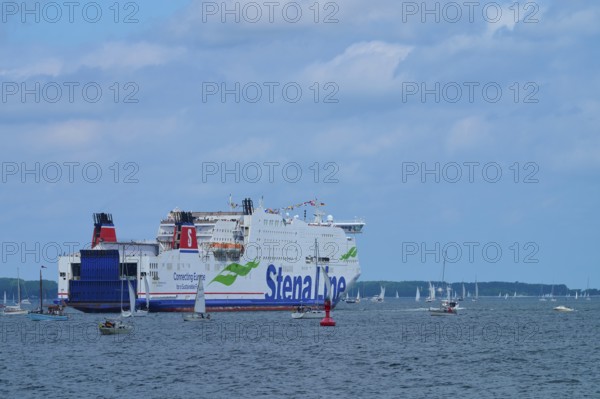 Large ferry on the sea surrounded by sailing boats under a slightly cloudy sky, Windjammer Parade Kiel 2025, Heikendorf, Kreis Plön, Kieler Förde, Schleswig-Holstein, Germany