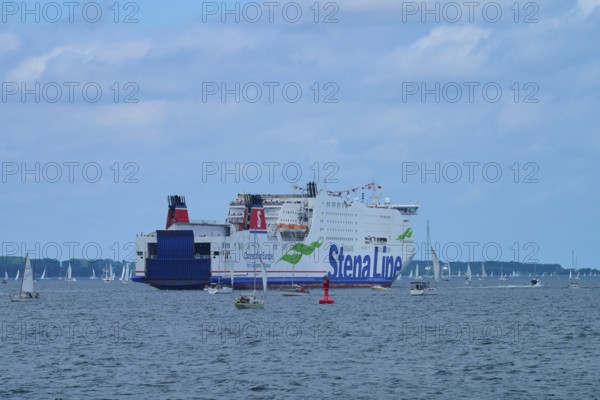 Large ferry on the sea surrounded by sailing boats under a blue sky, Windjammer Parade Kiel 2025, Heikendorf, Plön district, Kiel Fjord, Schleswig-Holstein, Germany