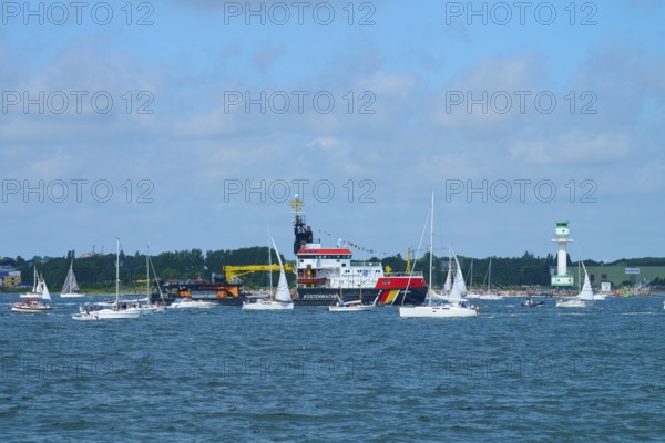 Various boats and a large ship Arkona Coast Guard on the sea next to a lighthouse Friedrichsort, Windjammer Parade Kiel 2025, district Plön, Kiel Fjord, Schleswig-Holstein, Germany