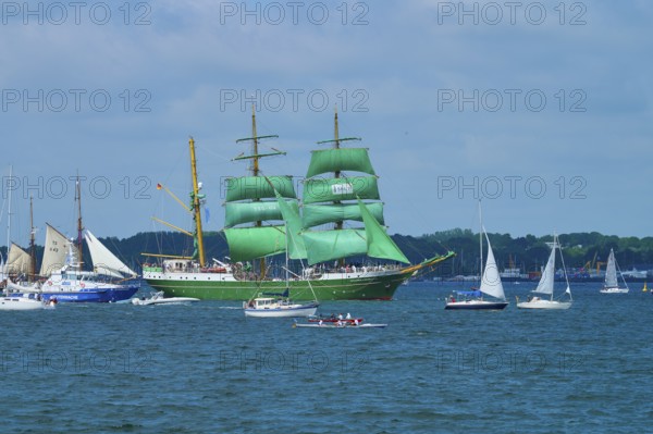 A large sailing ship with green sails Alexander von Humbold 2 and a group of smaller boats on the sea, Windjammer Parade Kiel 2025, Heikendorf, Plön district, Kiel Fjord, Schleswig-Holstein, Germany