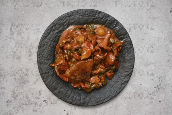 A hearty beef stew featuring tender chunks of meat and fresh vegetables sits invitingly on a textured black plate