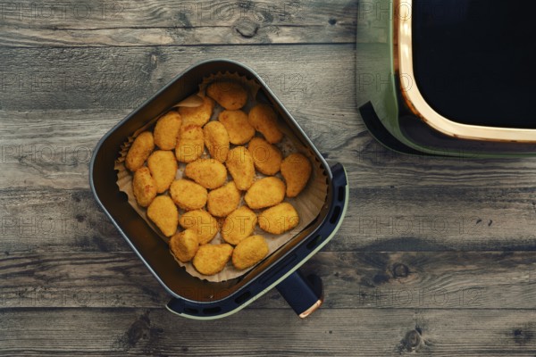 Golden and crispy chicken nuggets fill the air fryer basket, ready to be served as a tasty snack or meal. Their appetizing aroma and crunchy texture make them an irresistible choice