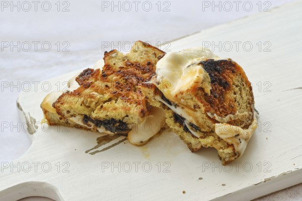 Cheese melts and blends together in a delightful three cheese sandwich resting on a rustic wooden board. The crust is golden brown, promising a crispy bite as flavors meld perfectly inside