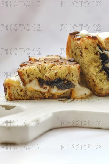 Melted cheese oozes from the sides of a perfectly toasted three cheese sandwich, showcasing a golden crust and savory filling