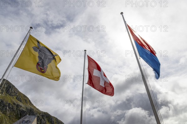 Flags of the cantons of Uri and Ticino and the Swiss flag waving in the wind, Gotthard Pass, Gottardo, Ticino, Switzerland