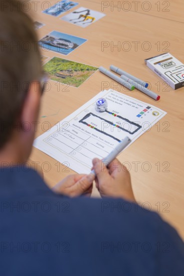 Man plans or documents on paper with markers and small robot on a table, Youth Research Centre