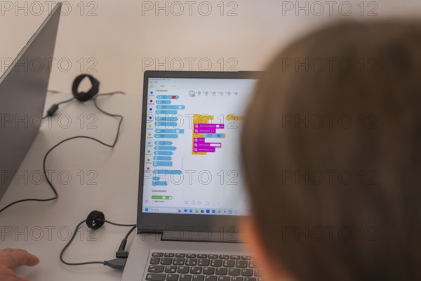 Two people working on laptops with a colourful programming interface, Youth Research Centre
