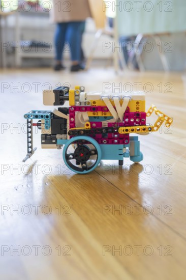 Colourful Lego robot with wheels on a wooden floor demonstrates technical creativity, Youth Research Centre