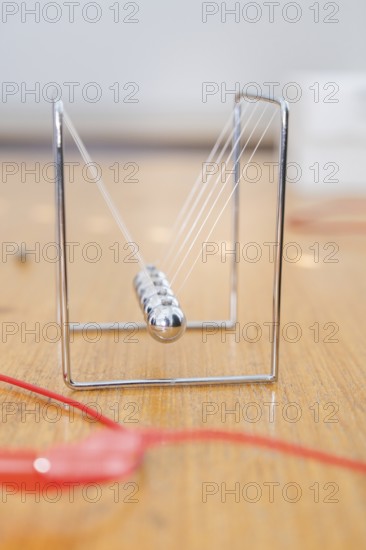Metallic Newton pendulum with resting spheres on a wooden table, Youth Research Centre