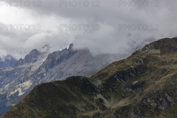 View over the Tremola to the Poncione di Fieud, the peaks of the Bedretto in the clouds, Passo Scimfuss, Airolo, Ticino, Switzerland