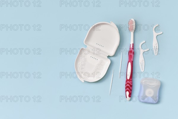 Top view of dental clear aligners, toothbrush, toothpicks and floss on blue background with copy space