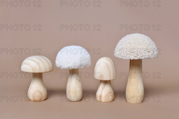 Four wooden mushroom ornaments in a row on beige background