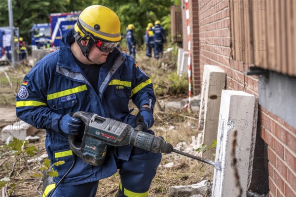 Rescue and recovery of people after a drone attack on residential buildings in a civil defence scenario, in which access is partly possible via wall breakthroughs or upper floors, simulated wall breakthrough with a concrete slab, FÜLEX25, of the THW, Technisches Hilfswerk, Landesverband North Rhine-Westphalia, on 4 weekends over 3500 volunteers from the 127 North Rhine-Westphalia local associations, many different deployment scenarios, from the field of disaster control and civil defence