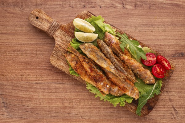 Fried crispy red mullet fish, on a wooden chopping board, with lime, no people