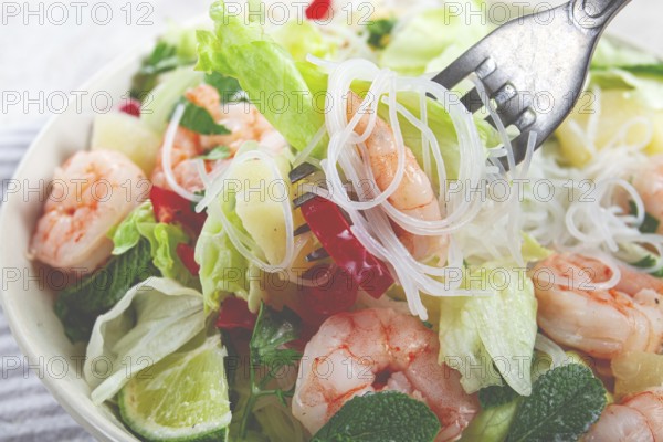 Thai salad with shrimp and rice noodles, pineapple slices, coriander and mint leaves, on a white plate, homemade, no people