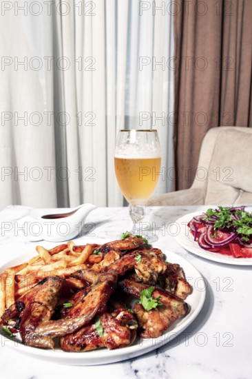Delicious barbecue chicken wings, with French fries, salad and a refreshing drink, at a cozy table, there are no people