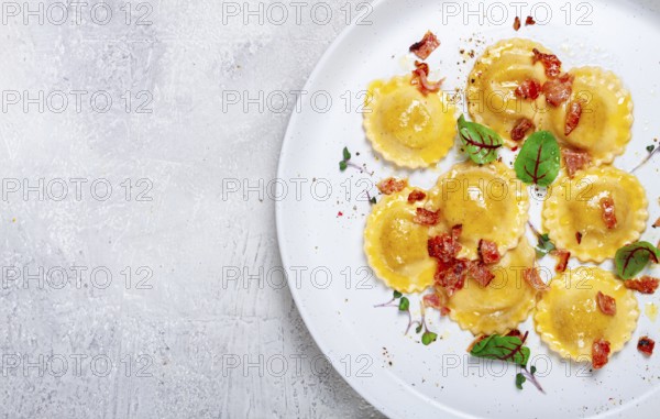 Fresh ravioli, with butter, spices and herbs, fried bacon, on the table, top view, light background, no people