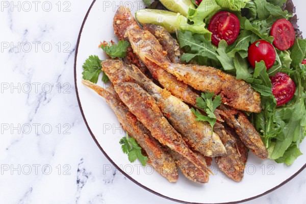 Fried crispy mullet fish, with fresh salad, on a plate with lime, no people