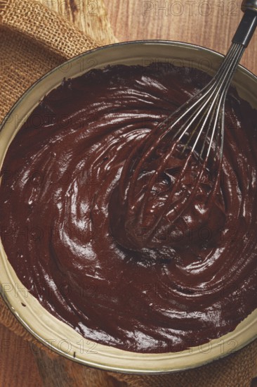 A bowl of chocolate dough, a whisk for whipping, baking, structure and consistency, homemade, top view, no people