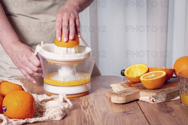 Preparation of freshly squeezed orange juice, using a juicer, in a cozy kitchen setting