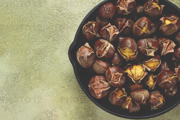 Roasted chestnuts, in an iron pan, wooden table, top view, no people, rustic style