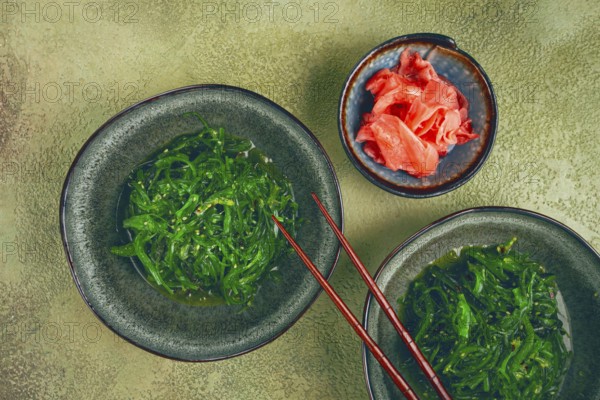 Chuka salad made from fresh seaweed, with sesame dressing, two bowls with chopsticks and pickled ginger, no people