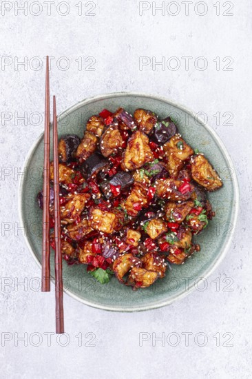 Fried eggplant, Chinese style, in sweet and sour sauce, with pepper and sesame seeds, in a green bowl
